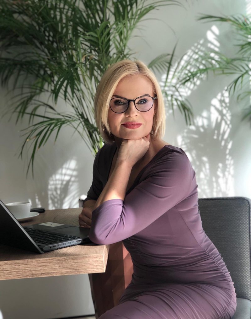 Woman in purple dress sitting next to the desk facing forward